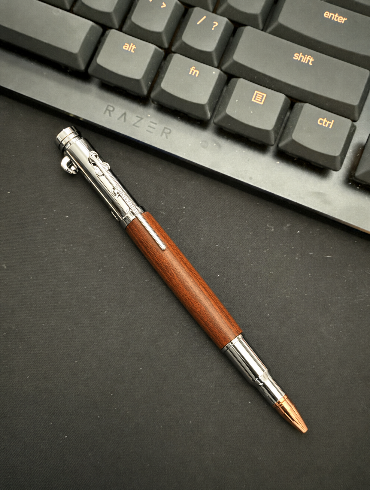 Wood and silver pen beside a computer keyboard