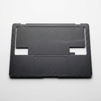 Dark slate gray carbon-style laptop skin sheet on matte off-white background