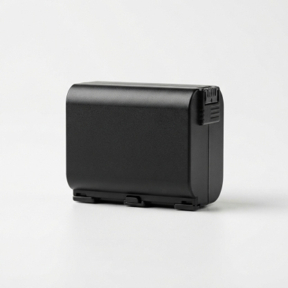 Black camera battery pack on matte off-white background