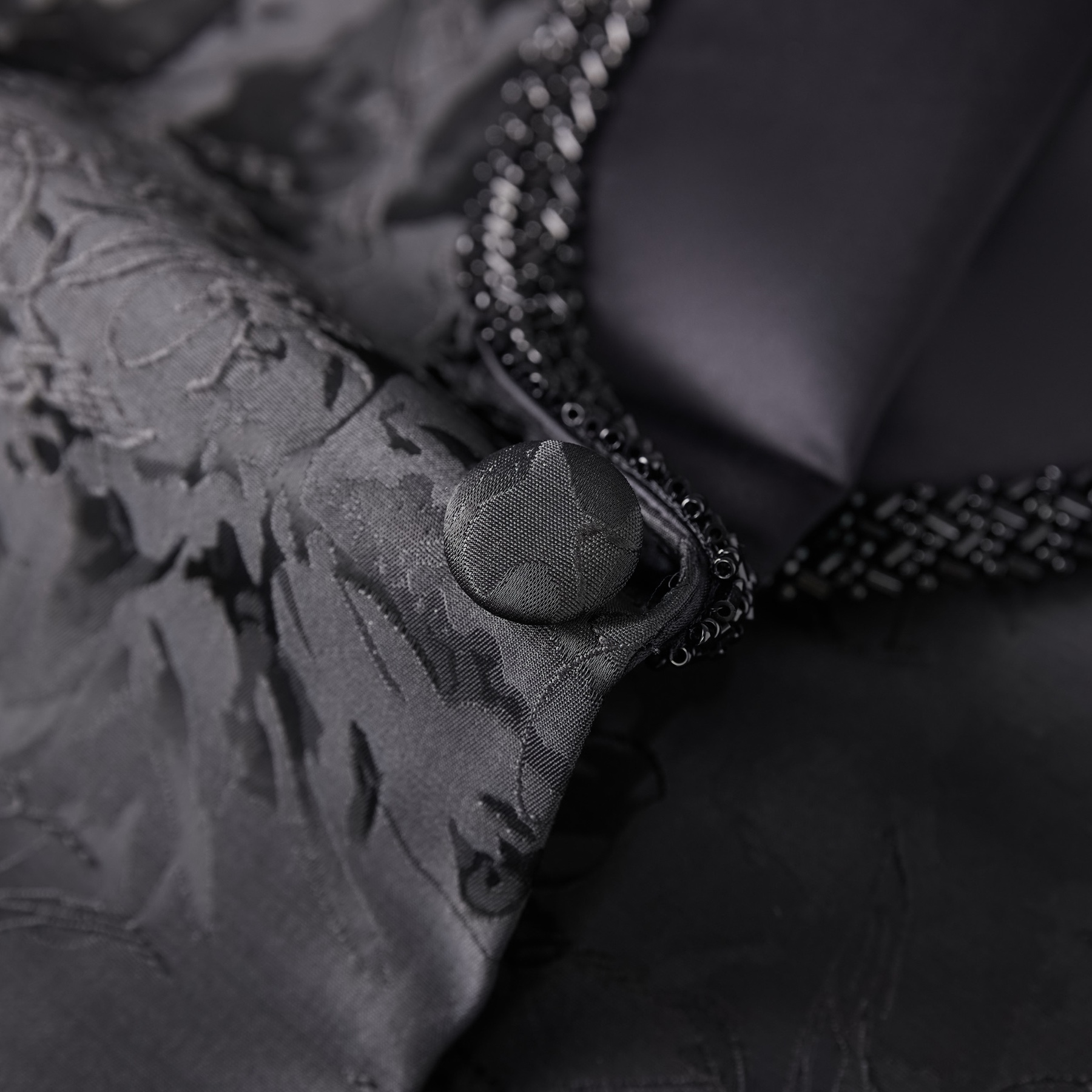 Men's black jacquard suit jacket with beaded shawl lapel and satin trim pockets, front view on a mannequin.