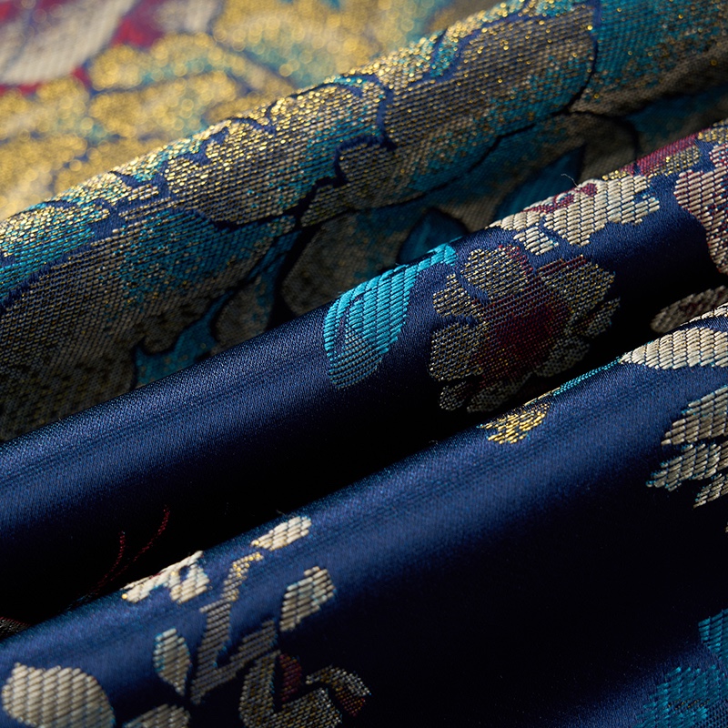 Men's blue floral brocade suit jacket with a one-button closure and intricate gold, teal, and red patterns.