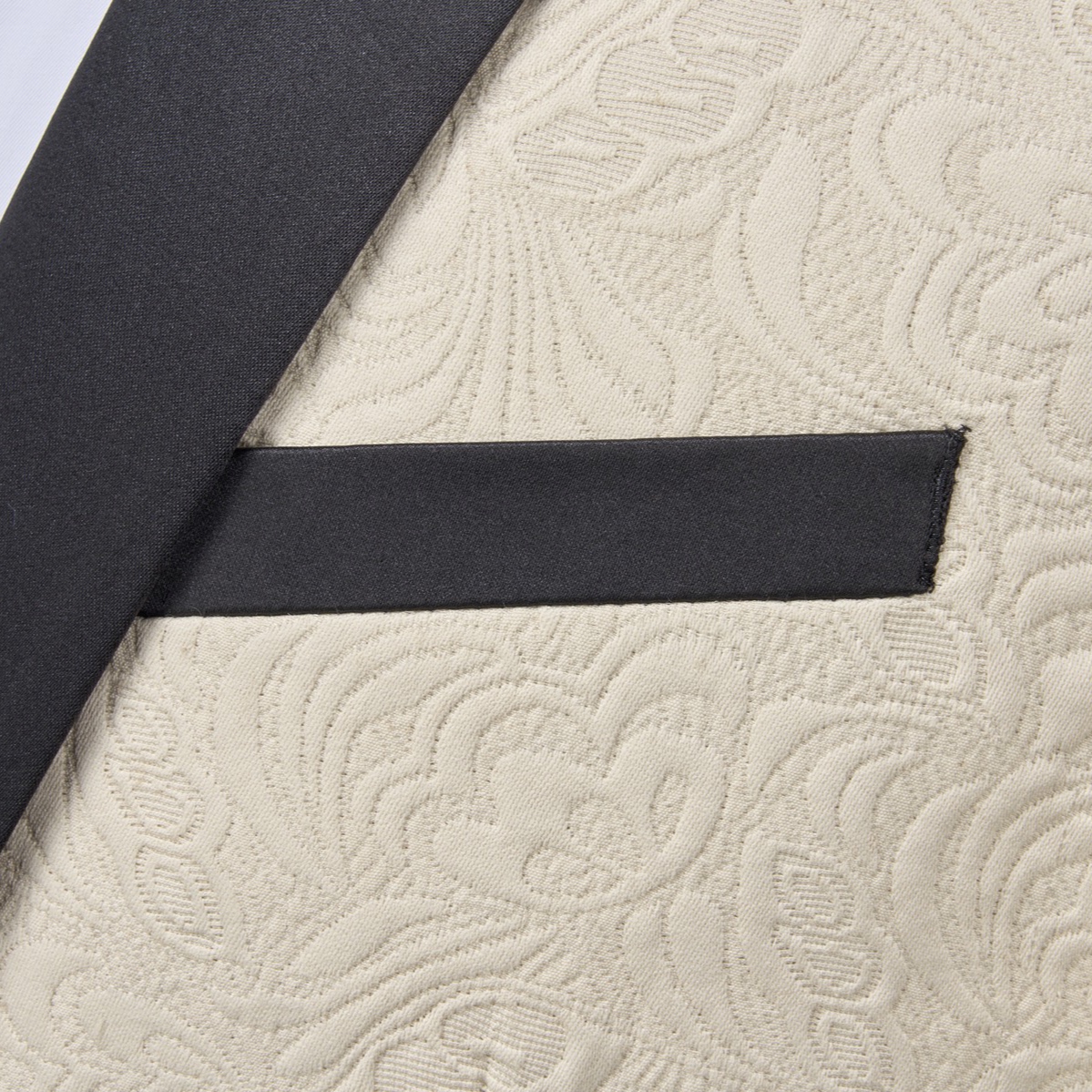 Front view of a men's cream jacquard tuxedo jacket with black satin shawl lapel and one-button closure