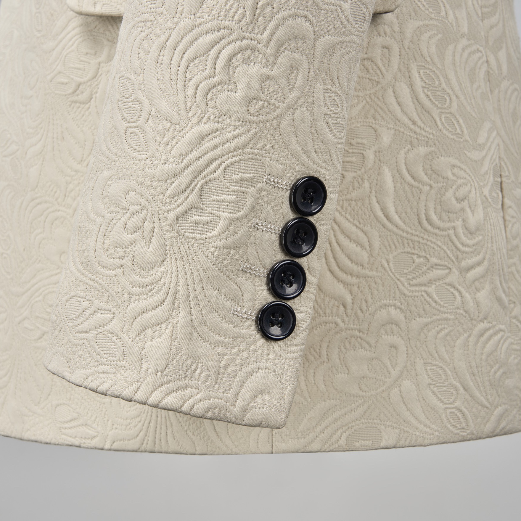 Front view of a men's cream jacquard tuxedo jacket with black satin shawl lapel and one-button closure