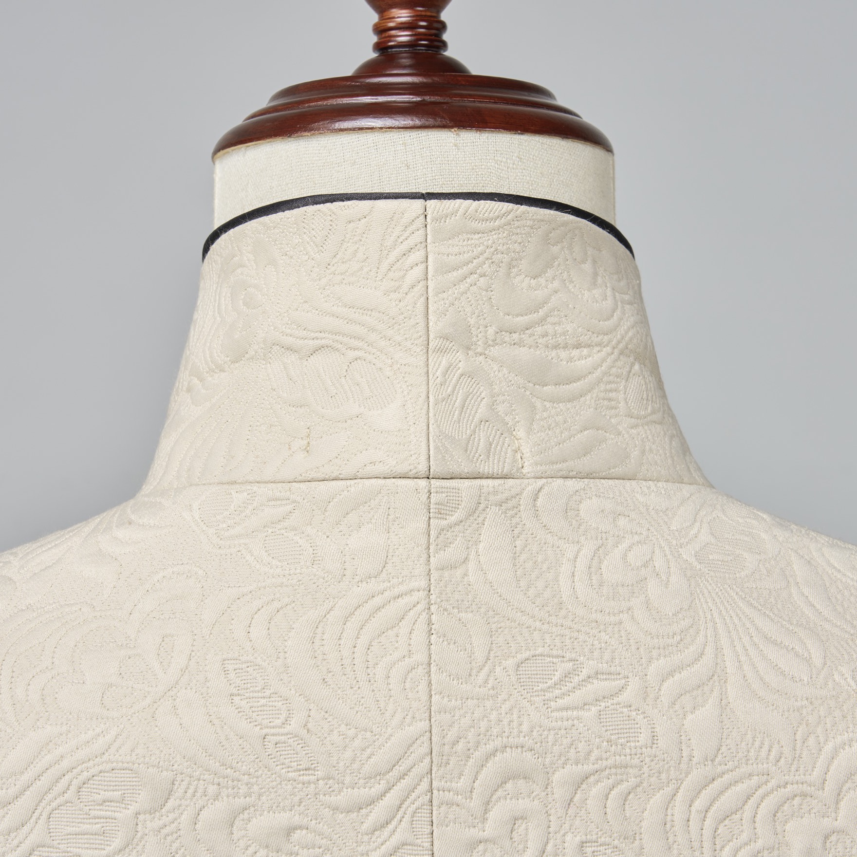 Front view of a men's cream jacquard tuxedo jacket with black satin shawl lapel and one-button closure