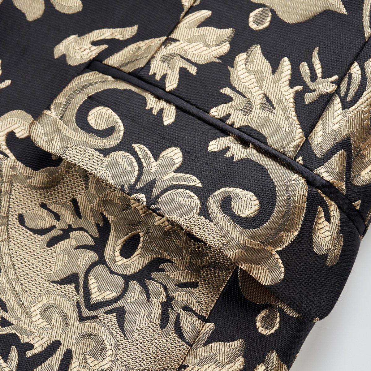 Front view of a men's black and gold damask patterned blazer with a black satin shawl lapel and one button closure.