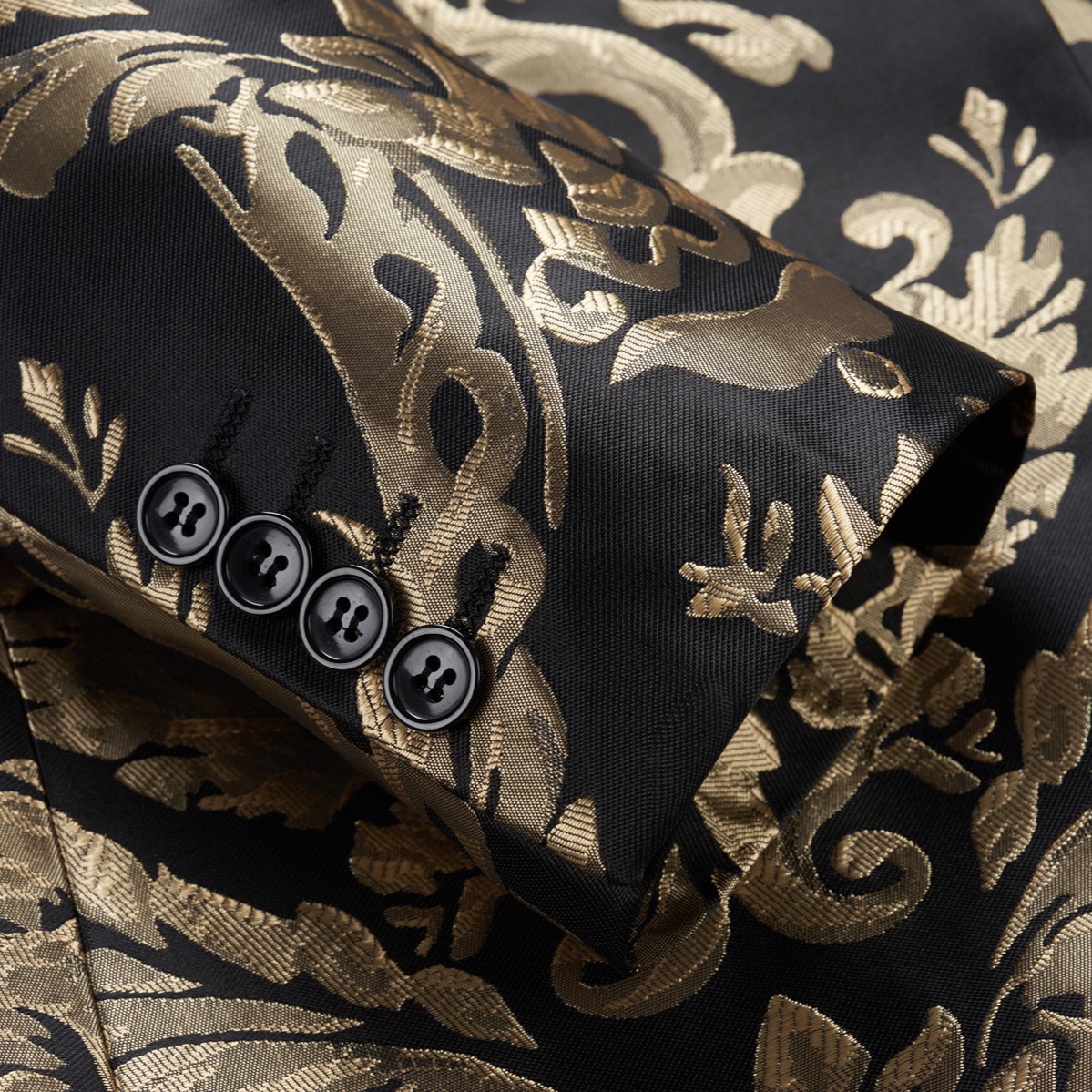 Front view of a men's black and gold damask patterned blazer with a black satin shawl lapel and one button closure.