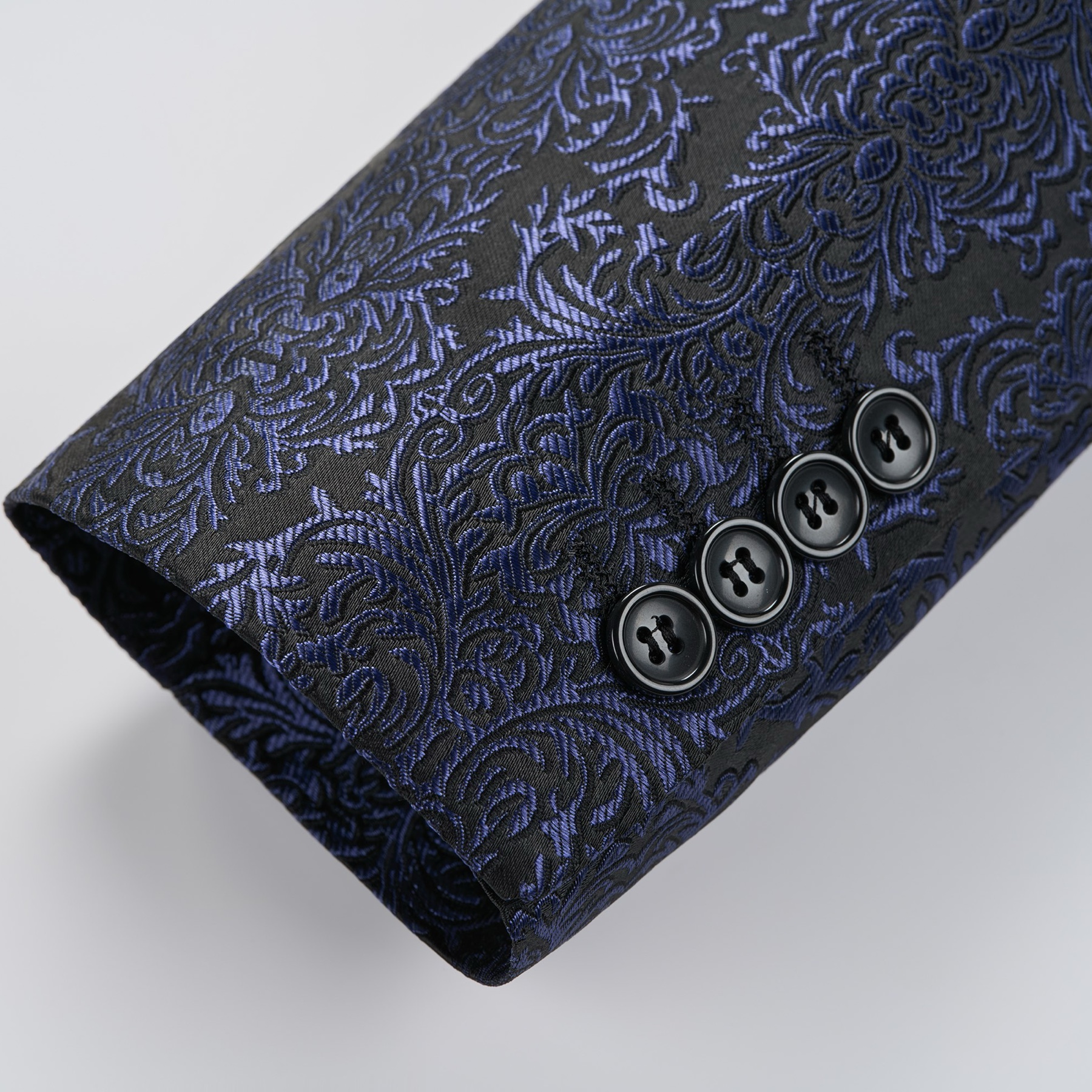 Front view of a men's black and navy damask pattern dinner jacket with a black satin shawl lapel and one-button closure.