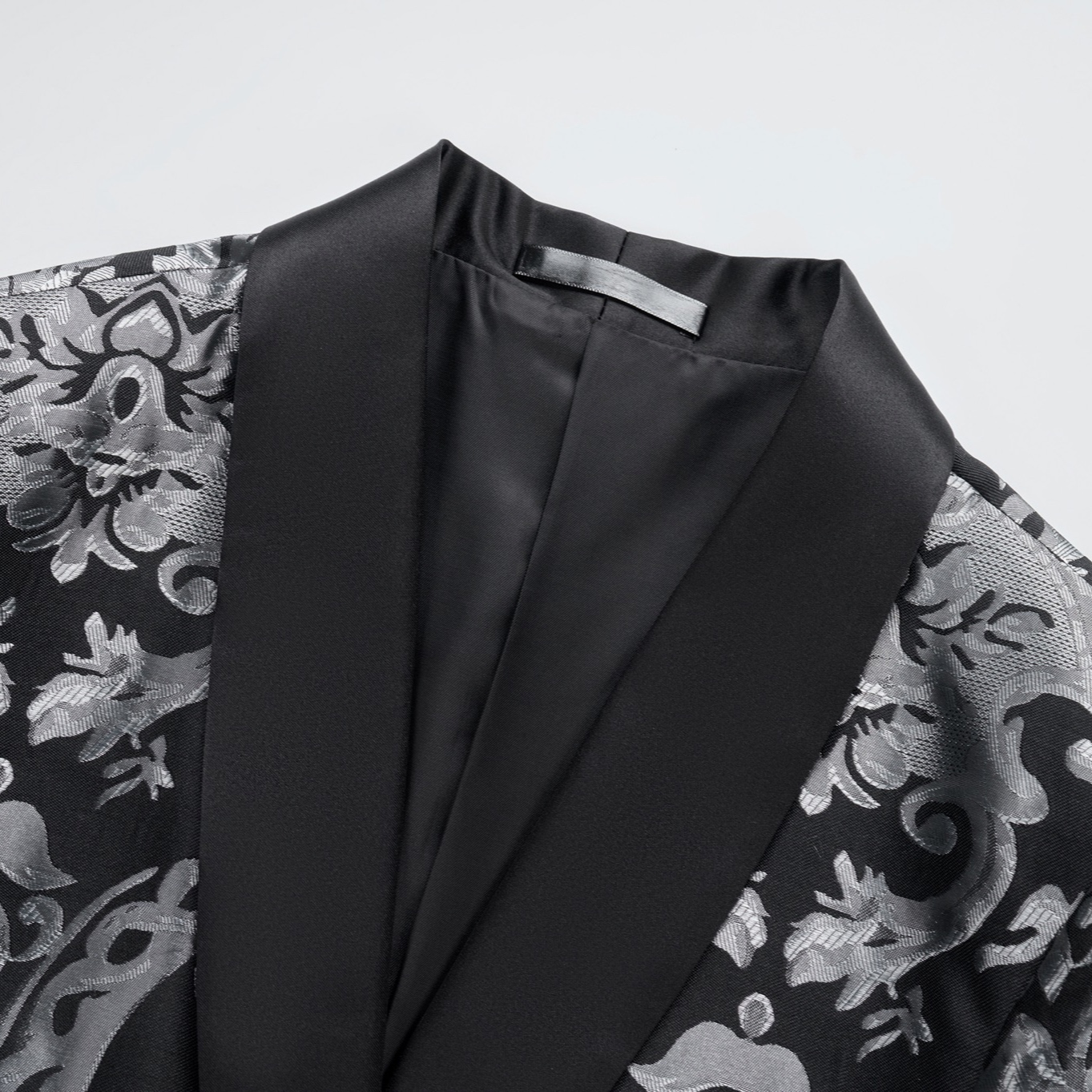 Front view of a men's black suit jacket with silver damask pattern and black satin shawl lapels.