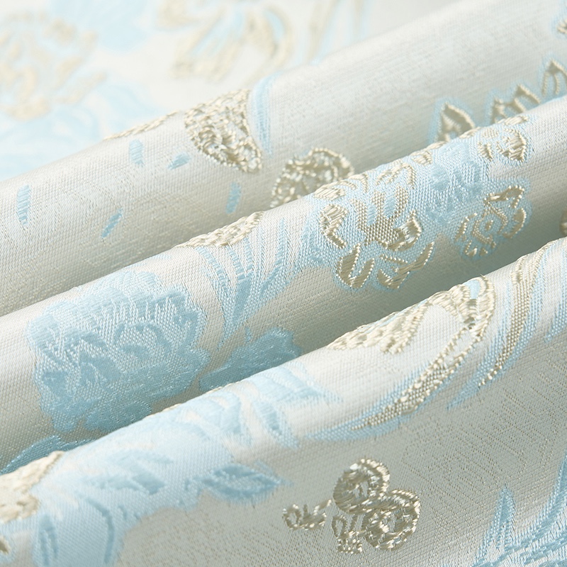 Close-up of a men's light blue and cream floral brocade suit jacket with a single marbled brown button.