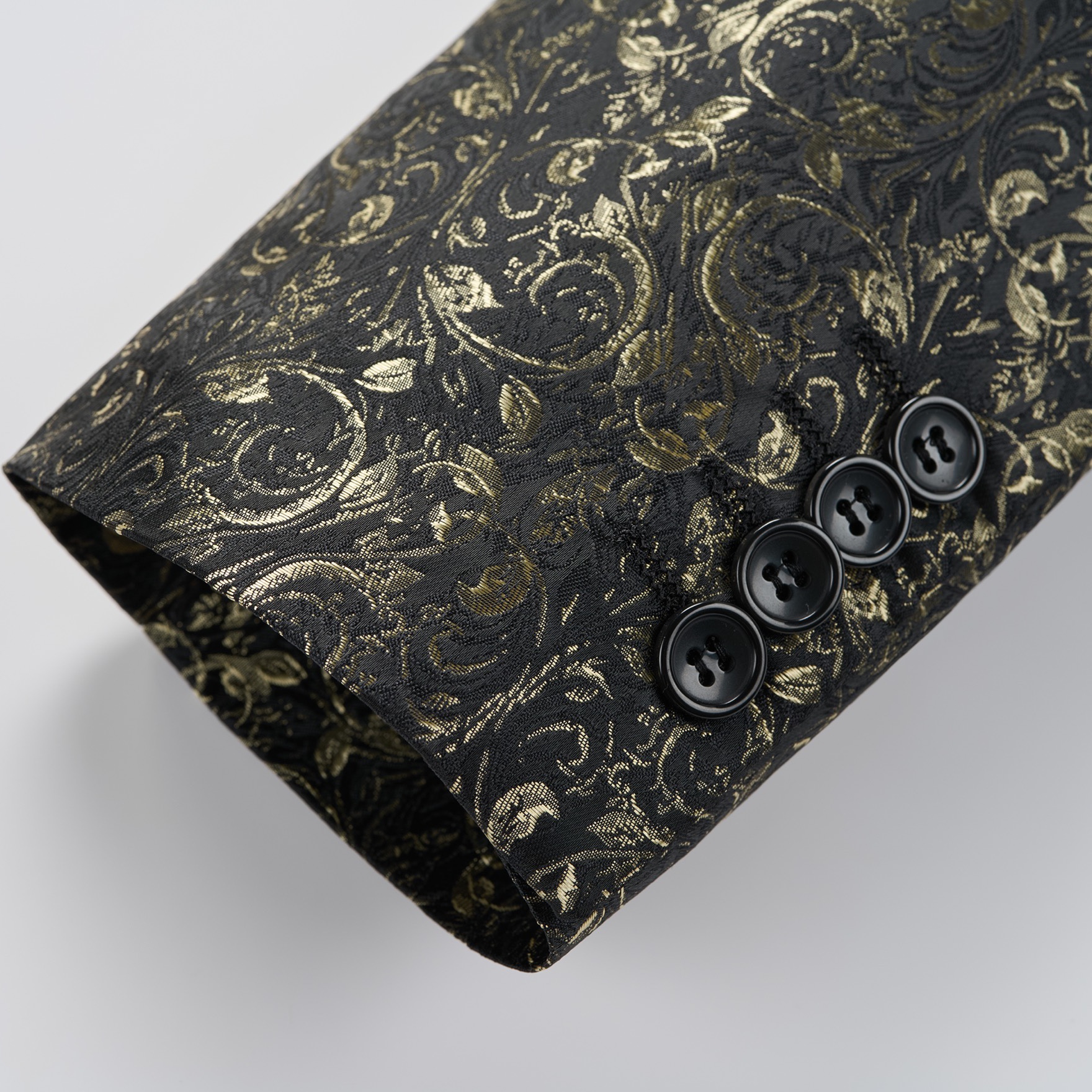 Front view of a men's black tuxedo jacket with gold floral jacquard pattern and black satin shawl lapel.