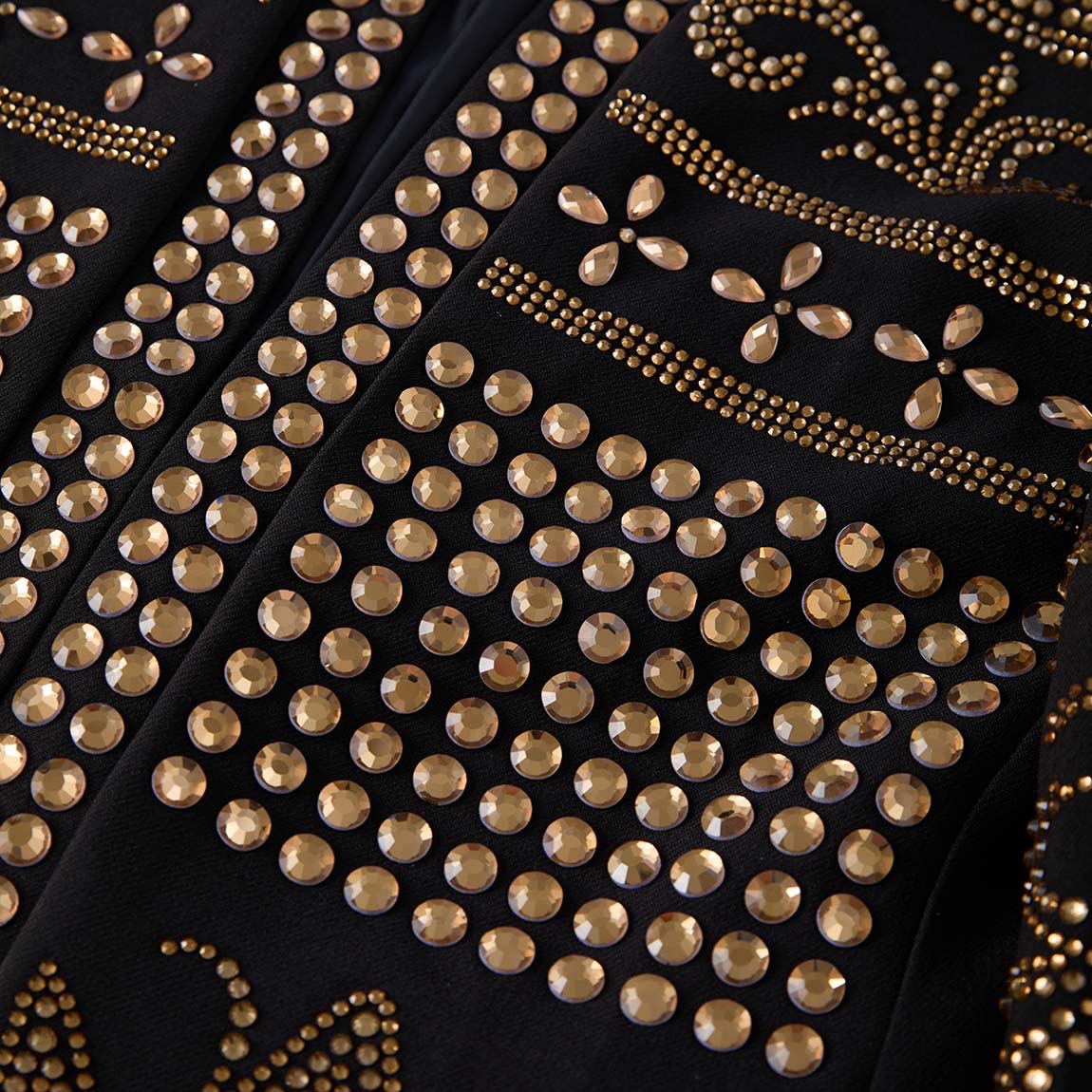 Front view of a black men's blazer adorned with gold studs forming crown and scroll patterns.