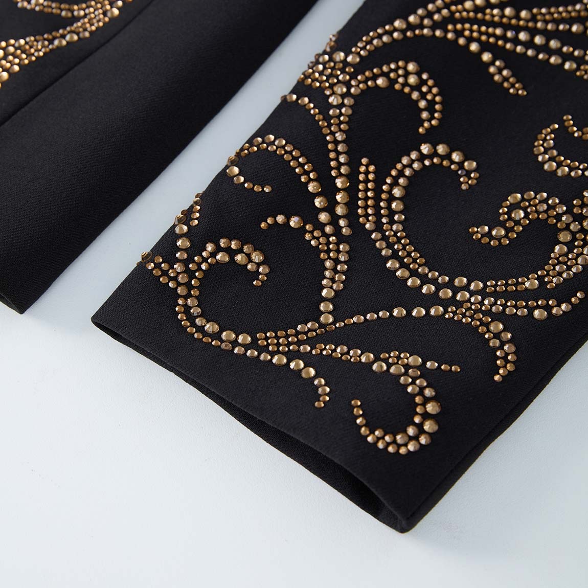Front view of a black men's blazer adorned with gold studs forming crown and scroll patterns.