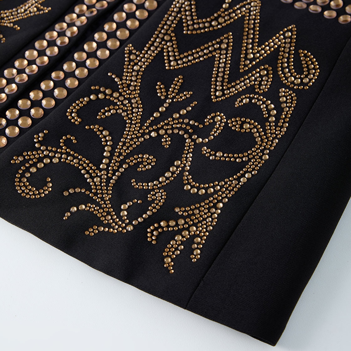 Front view of a black men's blazer adorned with gold studs forming crown and scroll patterns.