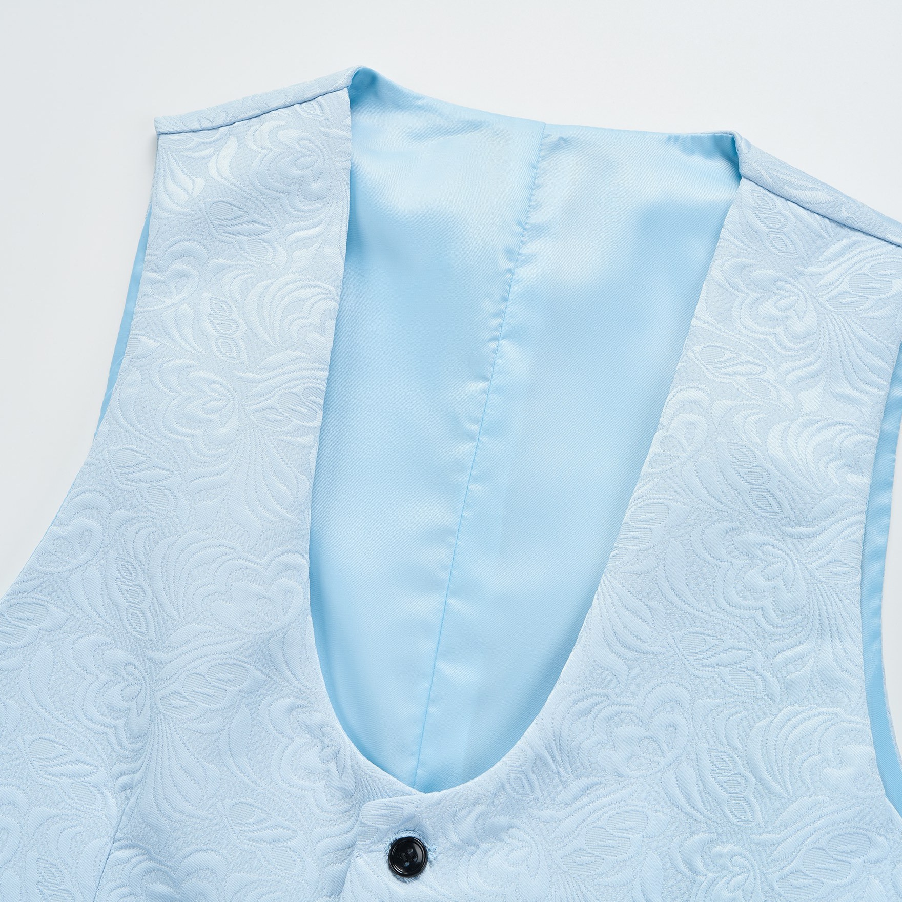 Front view of a light blue jacquard suit vest with black buttons and a V-neck.