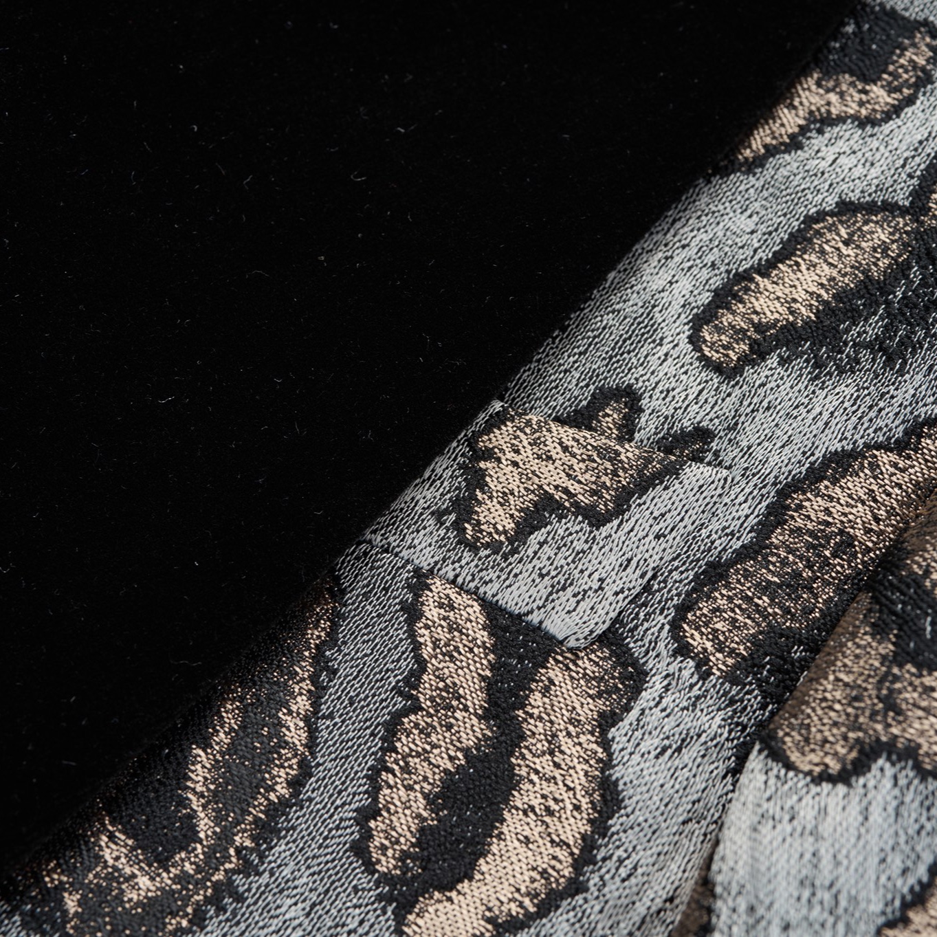 Front view of a men's black, gold, and grey leopard print tuxedo jacket with a black velvet shawl lapel and one-button