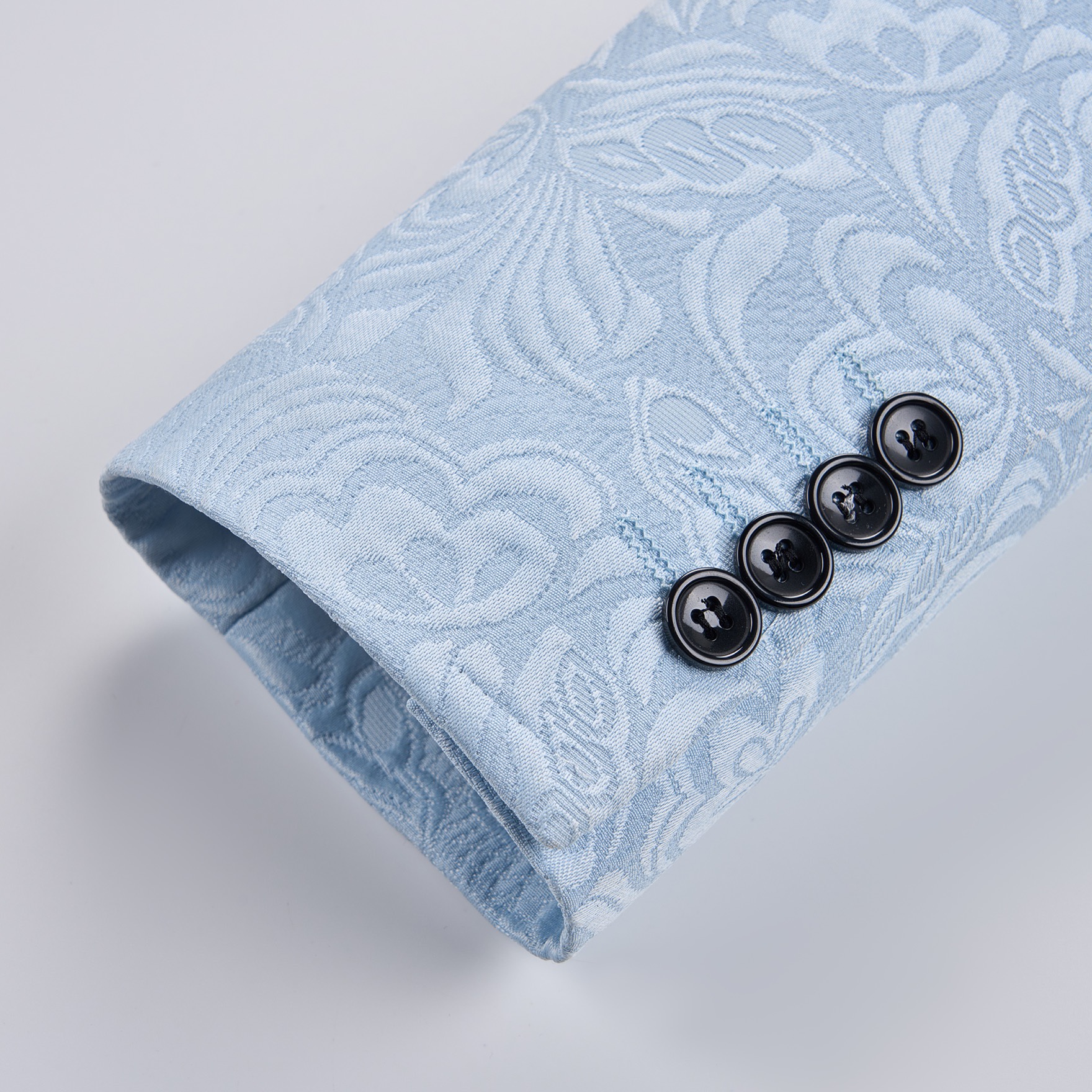 Front view of a men's light blue double-breasted blazer with a floral jacquard pattern and black shawl lapel.