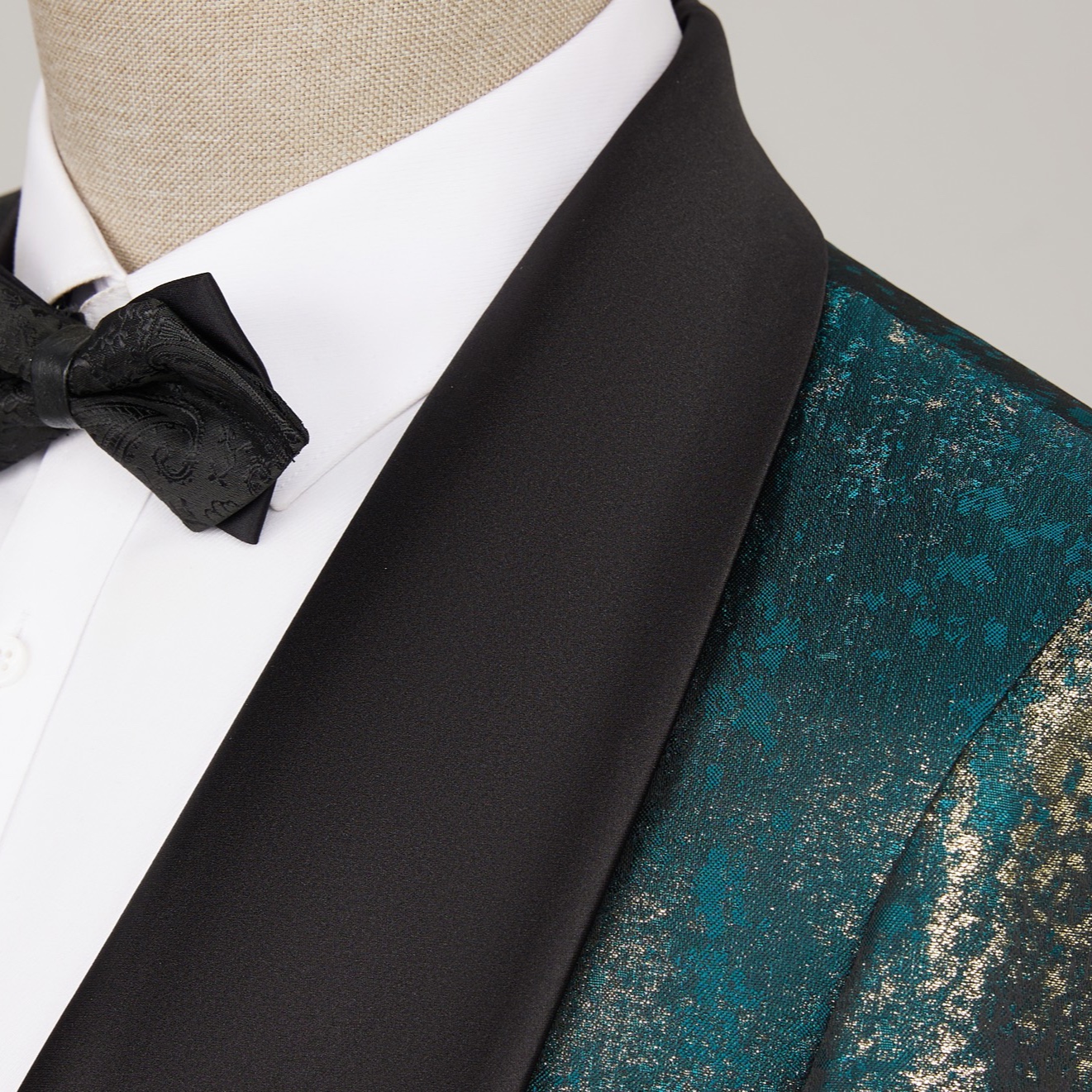 Back view of a men's teal and gold metallic print suit jacket with a black shawl lapel.