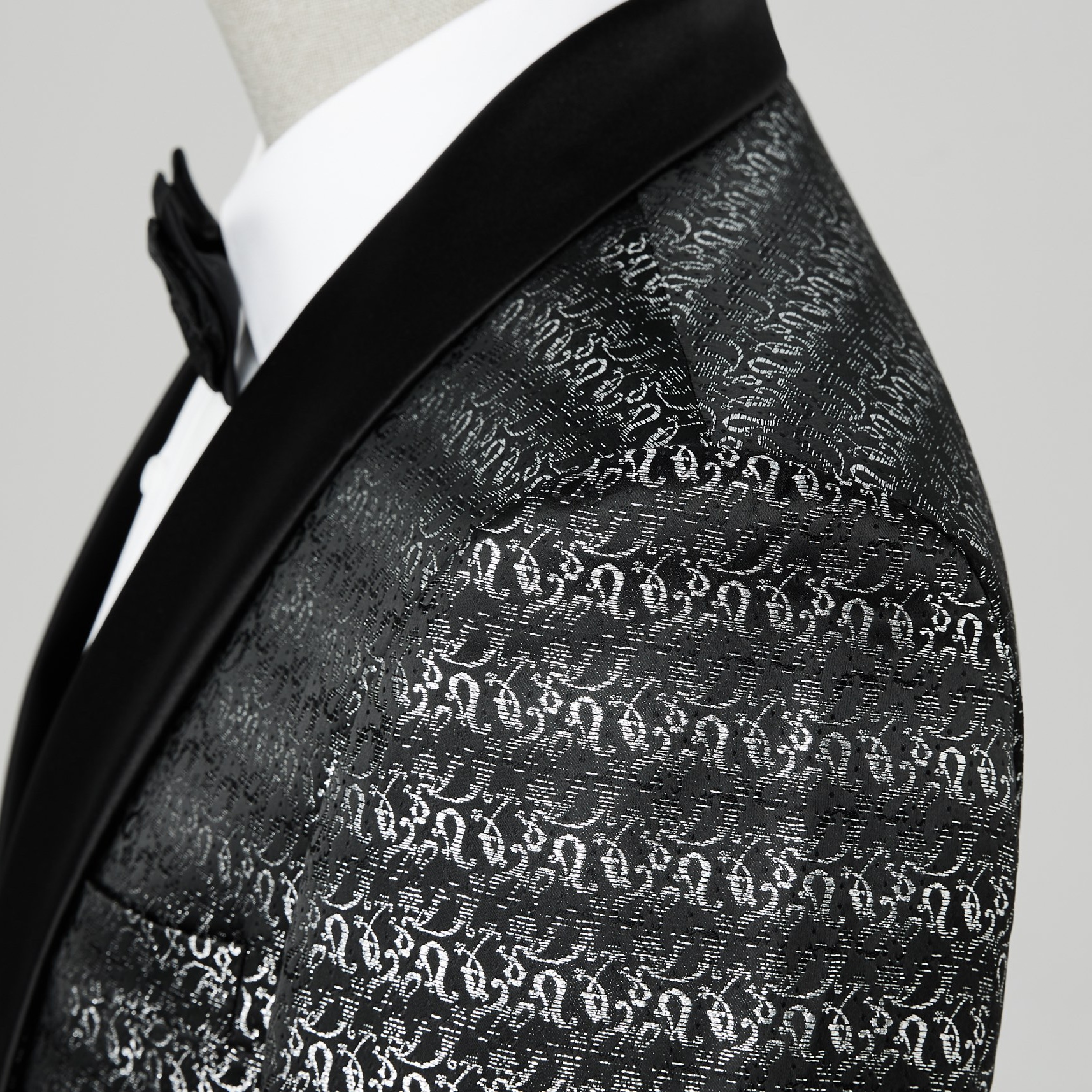 Front view of a men's black and silver patterned tuxedo jacket with a satin shawl lapel.