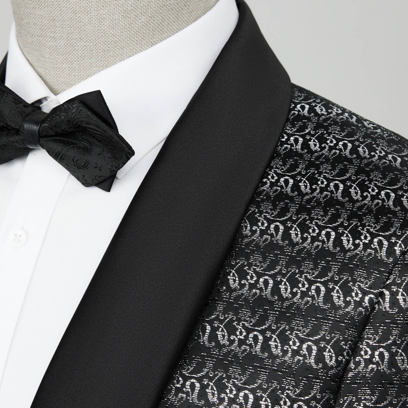 Front view of a men's black and silver patterned tuxedo jacket with a satin shawl lapel.