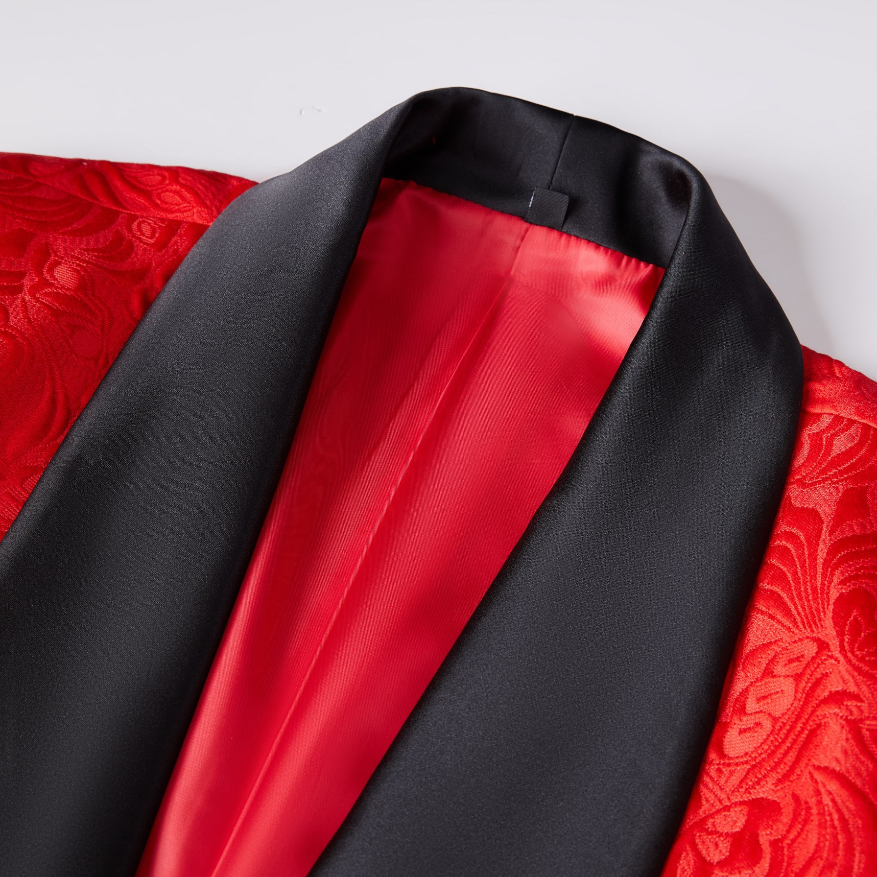 Back view of a men's red floral jacquard blazer with a black shawl lapel and sleeve buttons.