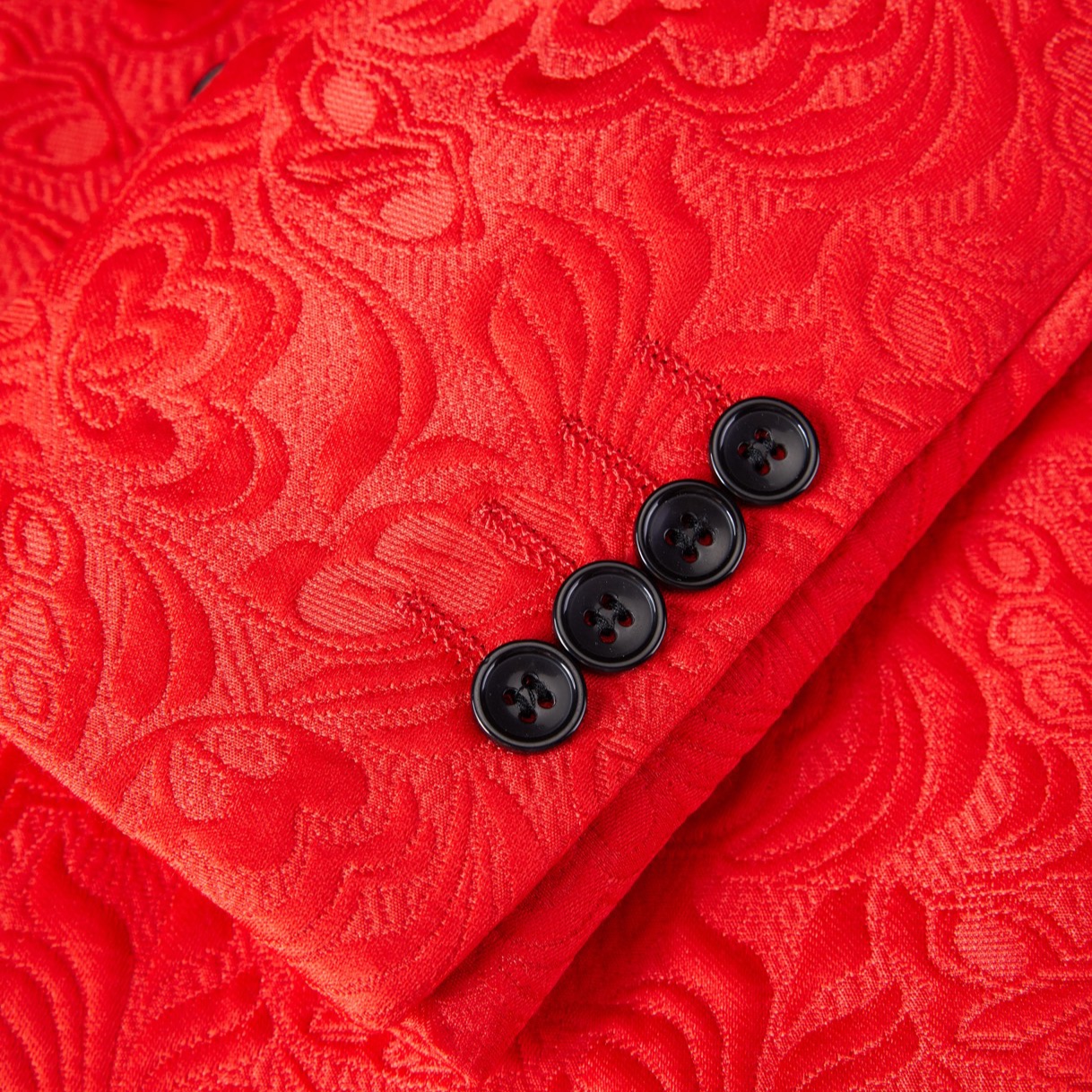 Back view of a men's red floral jacquard blazer with a black shawl lapel and sleeve buttons.