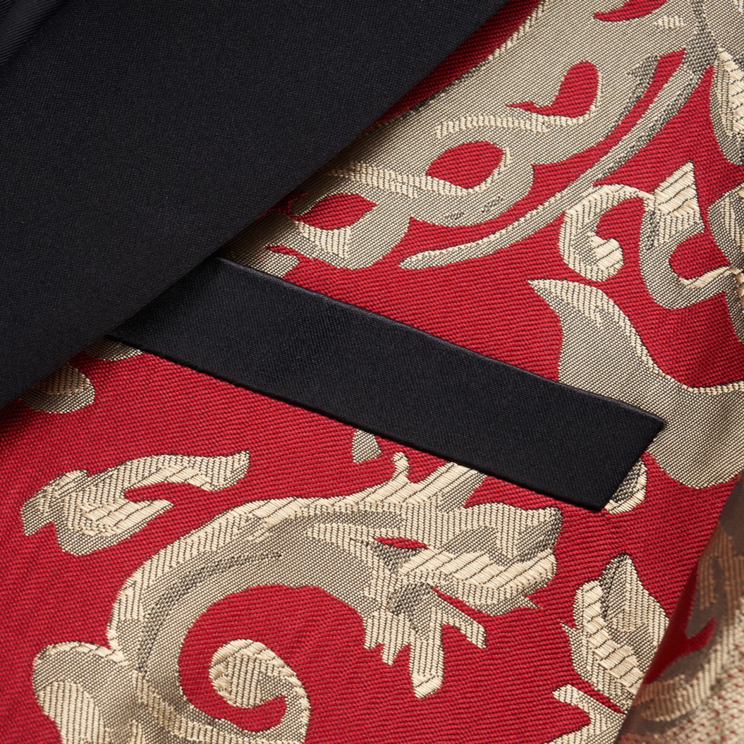 Front view of a men's red and gold jacquard patterned tuxedo jacket with black shawl lapel and one button closure.