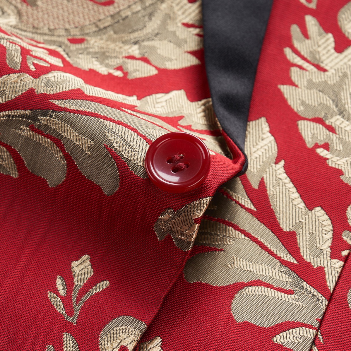 Front view of a men's red and gold jacquard patterned tuxedo jacket with black shawl lapel and one button closure.