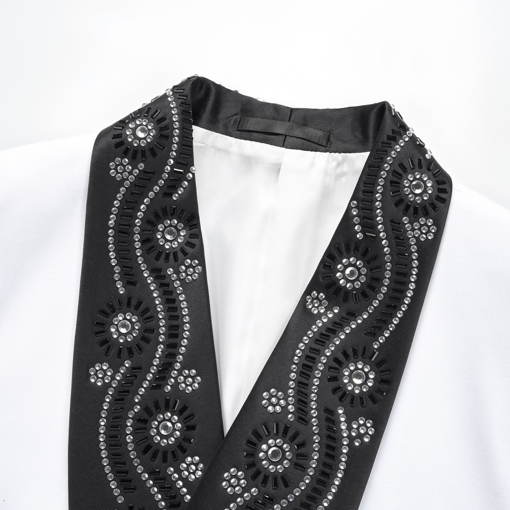 Front view of a white double-breasted suit jacket with black embellished shawl lapels and cuffs featuring rhinestones and