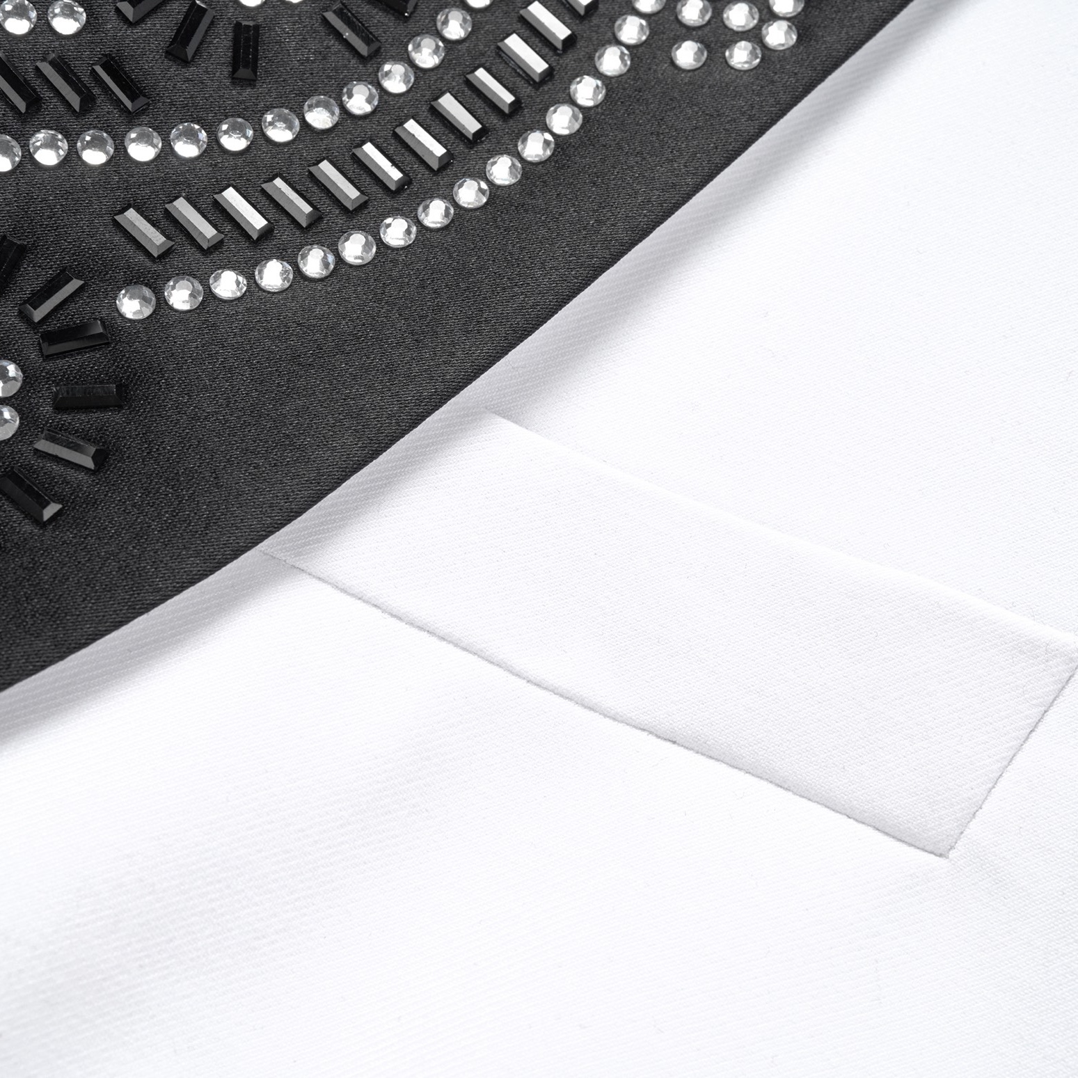 Front view of a white double-breasted suit jacket with black embellished shawl lapels and cuffs featuring rhinestones and