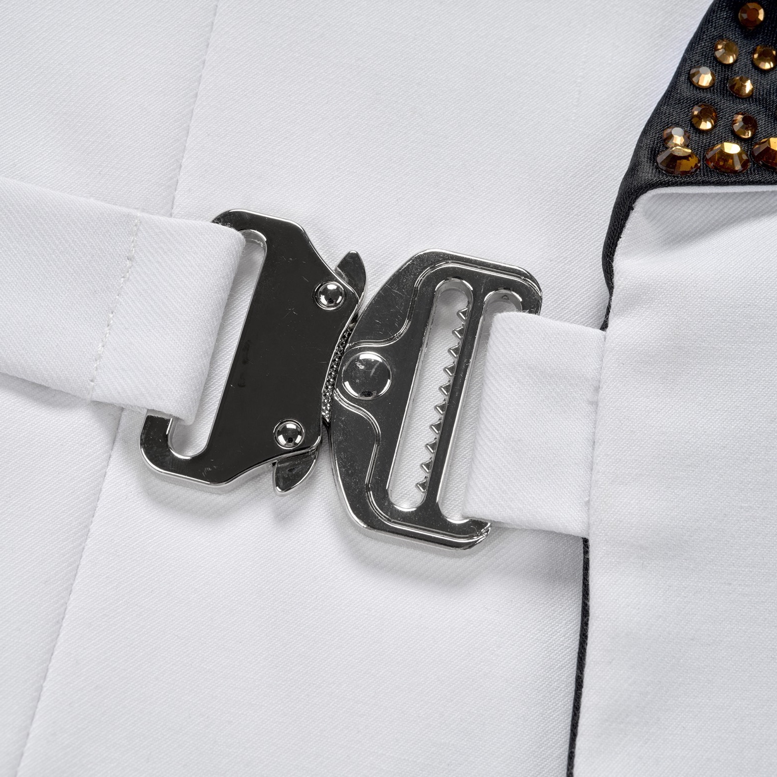 Front view of a men's white tuxedo jacket featuring a black rhinestone-embellished shawl lapel, a unique silver buckle
