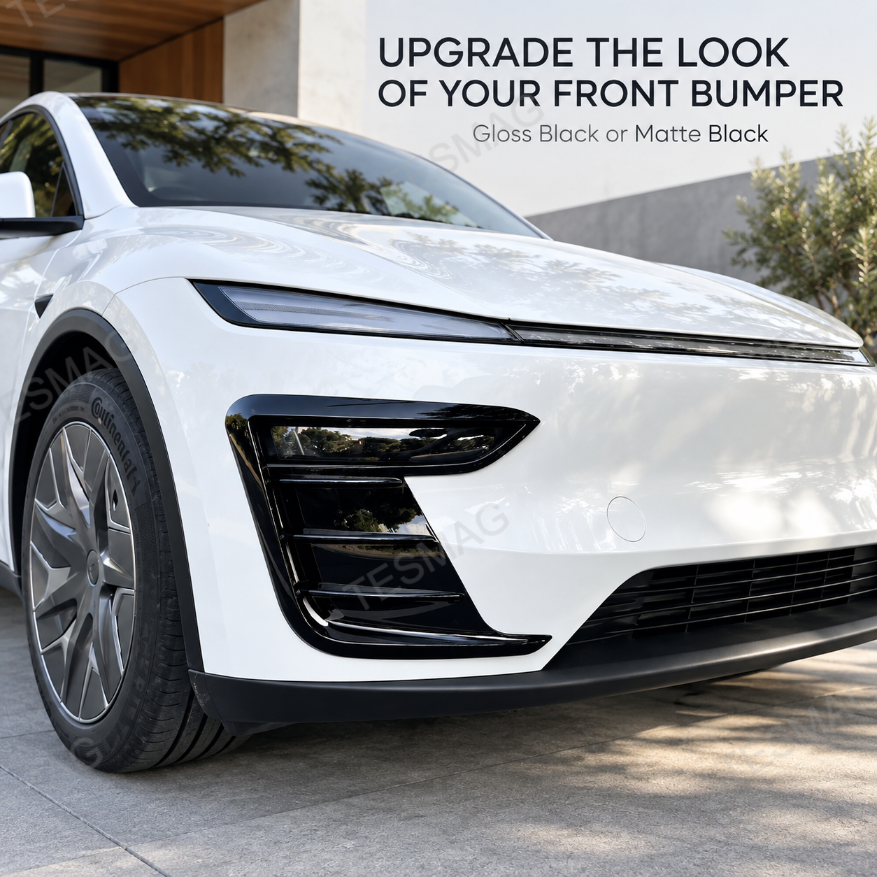 Close-up of gloss black front bumper trim installed on a white Model Y Juniper