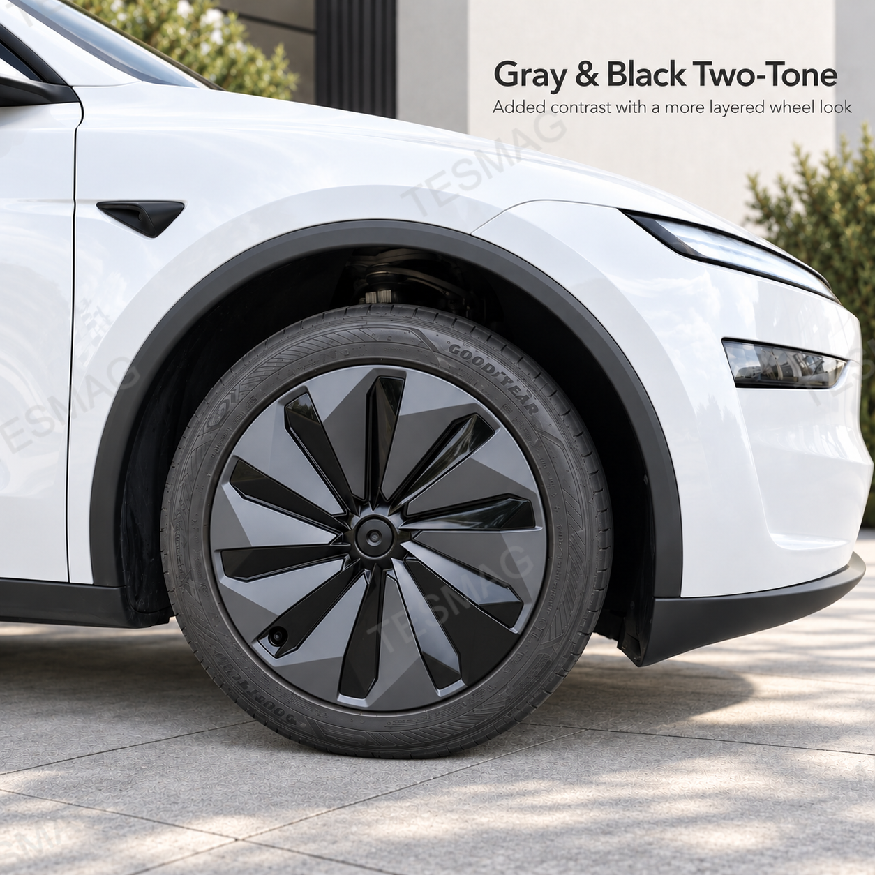 Gray and black two-tone wheel cover fitted to a white Tesla Model Y Juniper