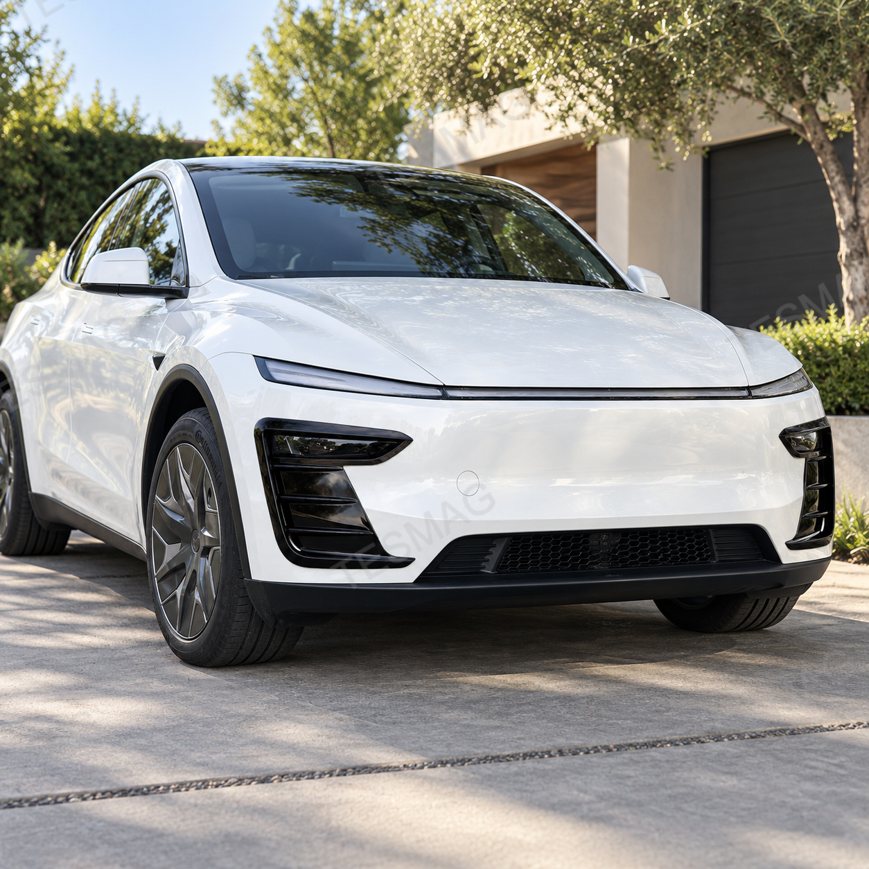 White Model Y Juniper with gloss black front bumper accent trim in a modern driveway