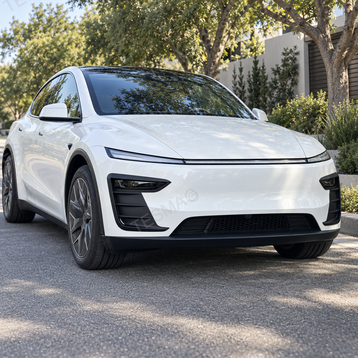 White Model Y Juniper with matte black front bumper accent trim on a tree-lined street