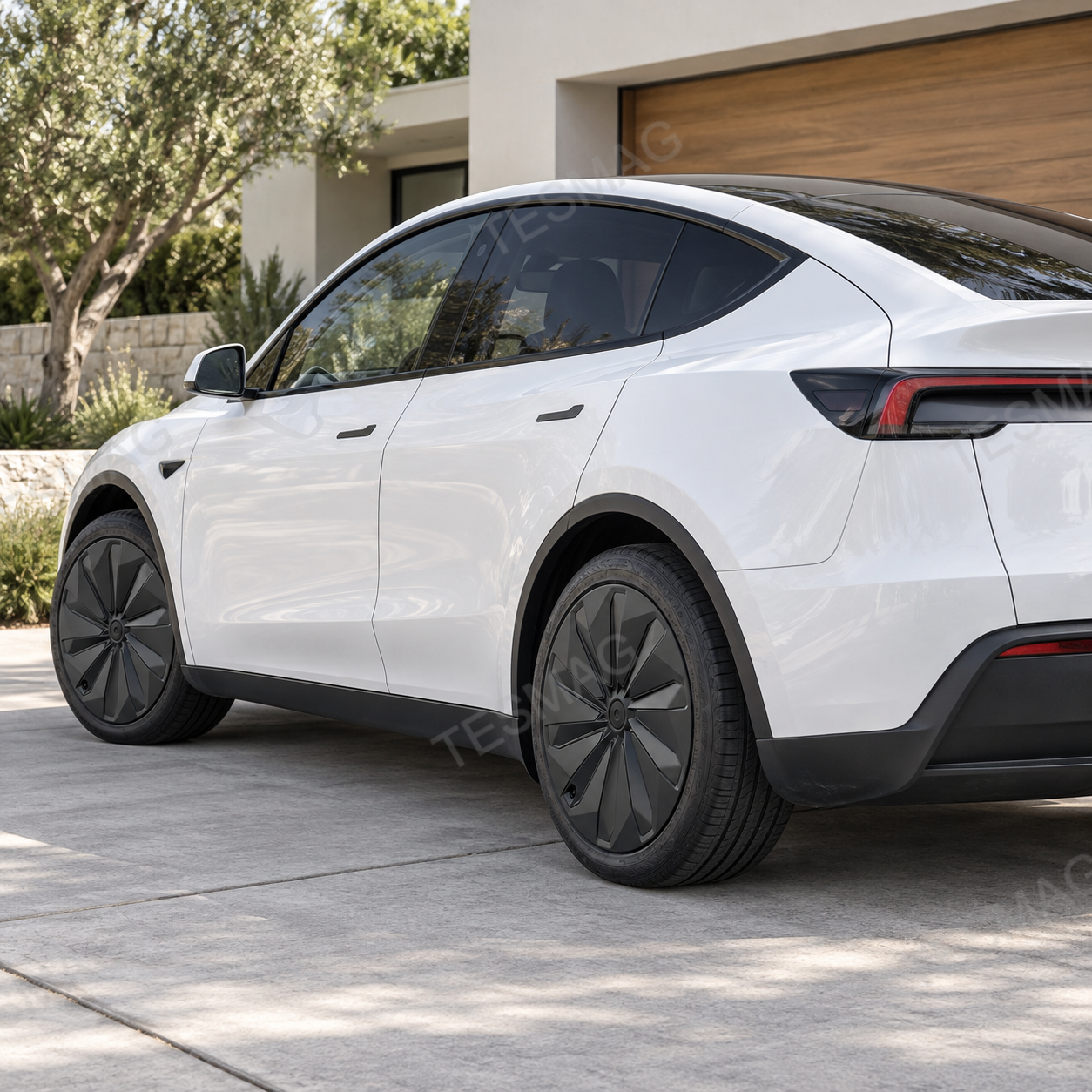 White Tesla Model Y Juniper rear three-quarter view with matte black wheel covers