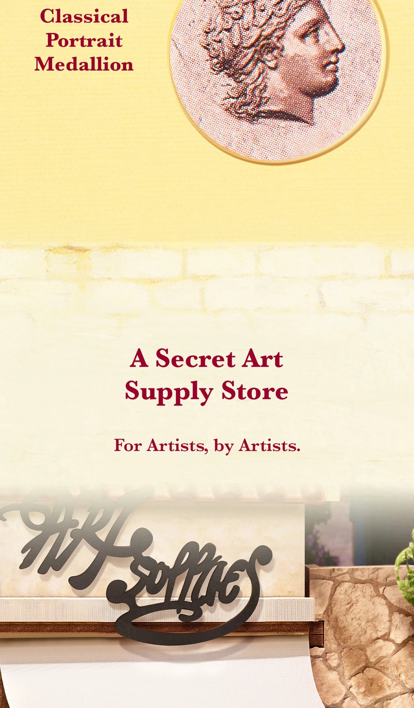 Close-up of a miniature art supply shop facade with a classical portrait medallion, cream brick wall, and a black script sign above a rolled paper awning.