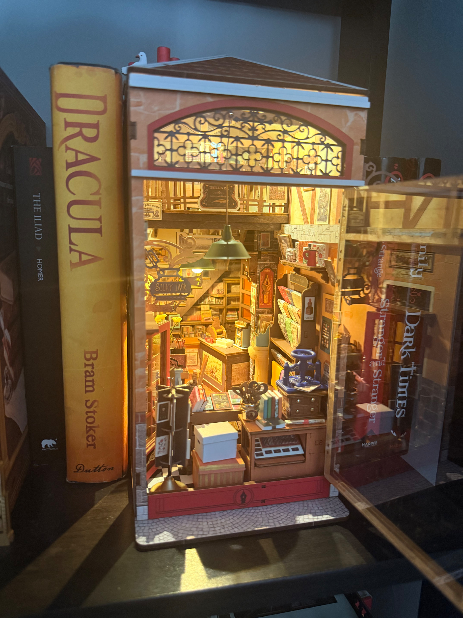Wisdom Stationery Shop displayed between books with its front window open, photographed by Orangesareus