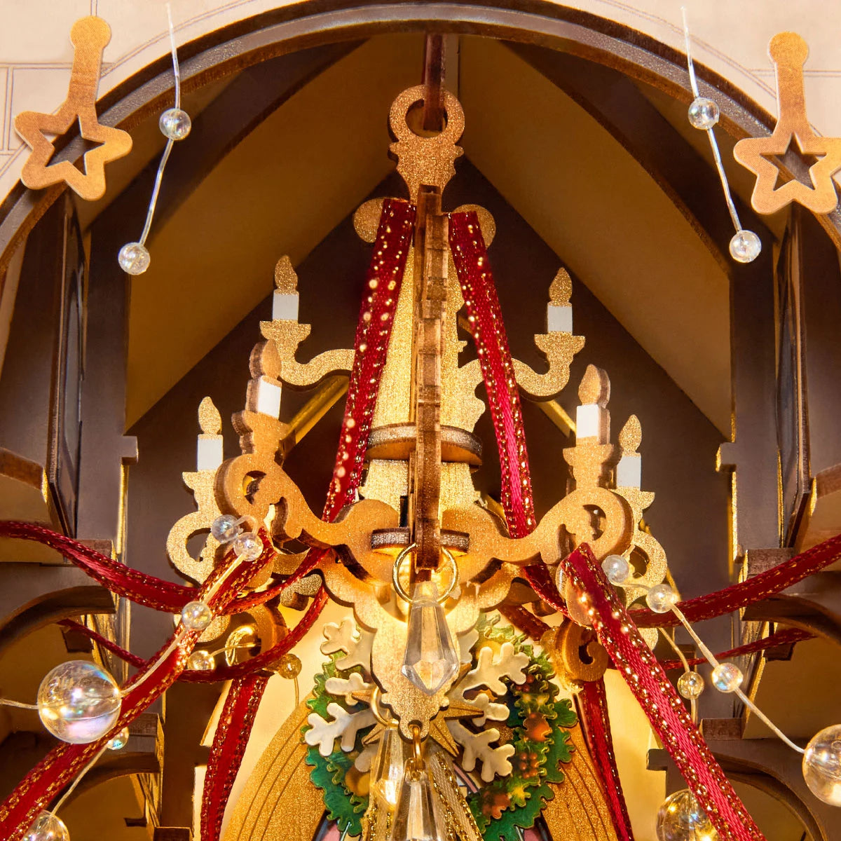 Crystal-style chandelier with candles, red ribbons, beads, and a wreath inside the miniature cathedral