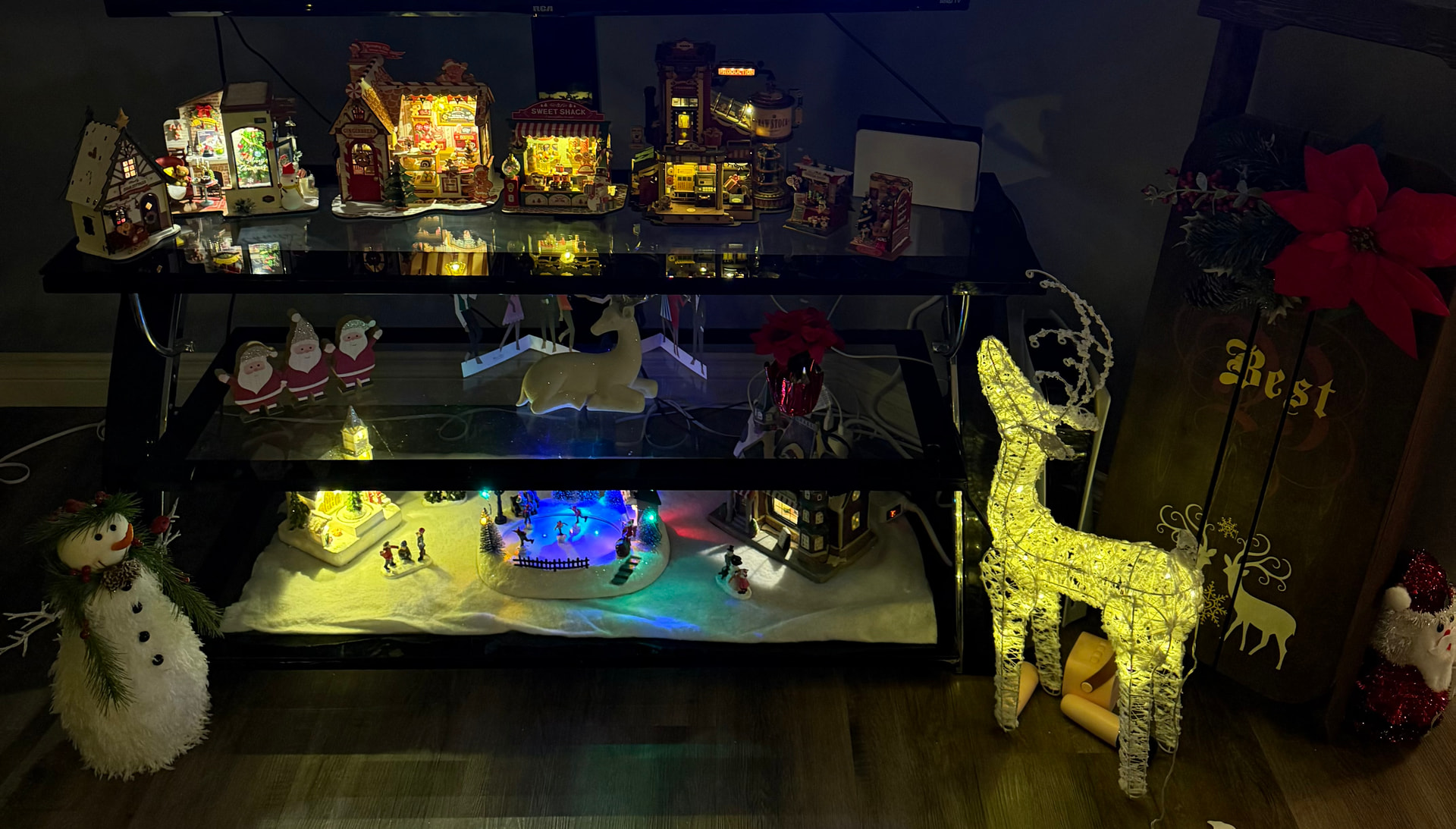La collection de miniatures de Noël de Rolife Community maker Atropex disposée sur un meuble TV et les étagères en dessous.