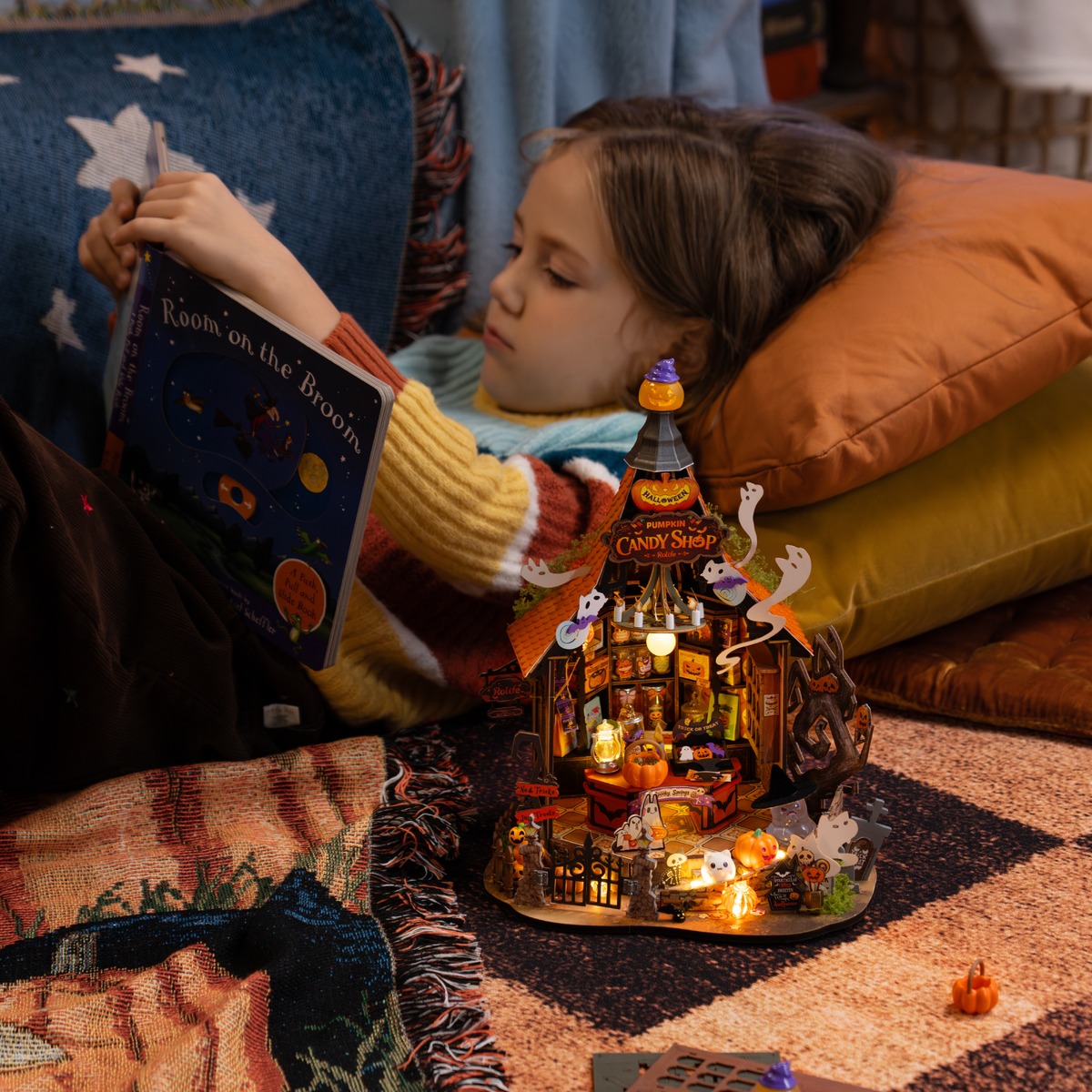 Beginner reading instructions beside an illuminated Haunted Candy House miniature