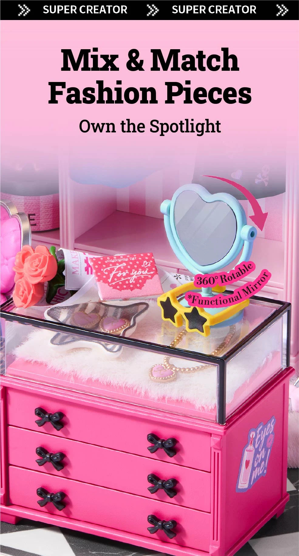 Pink miniature dresser with black bow handles and clear display top holding a heart-shaped mirror, star sunglasses, flowers and jewellery on faux fur.