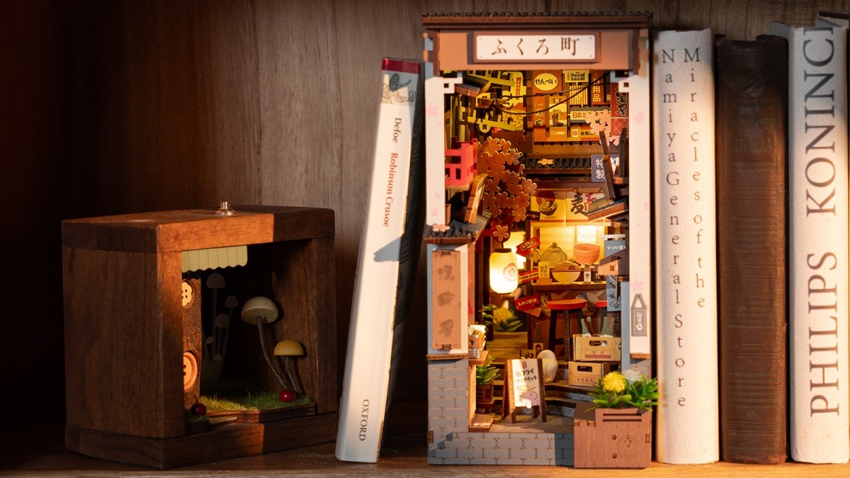 A warmly lit book nook displayed between books on a home bookshelf