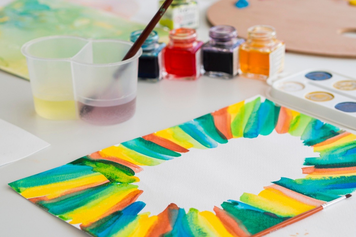 Colorful painting project with brushes, paints, and water cups on a table