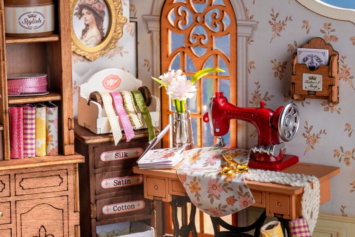 Miniature sewing corner filled with thread, fabric, and needlework details