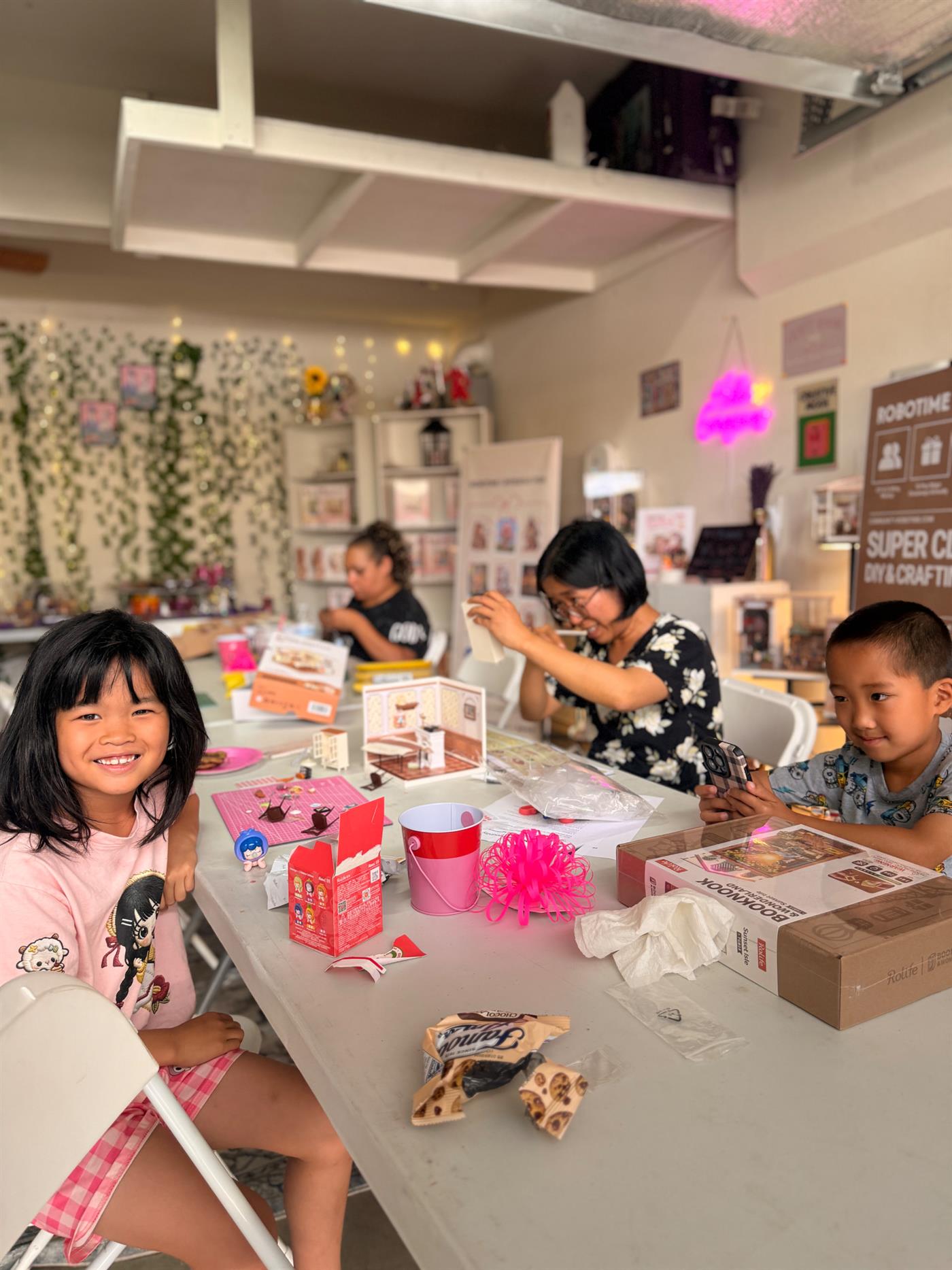 Children and adults build Rolife miniature kits together around a craft table