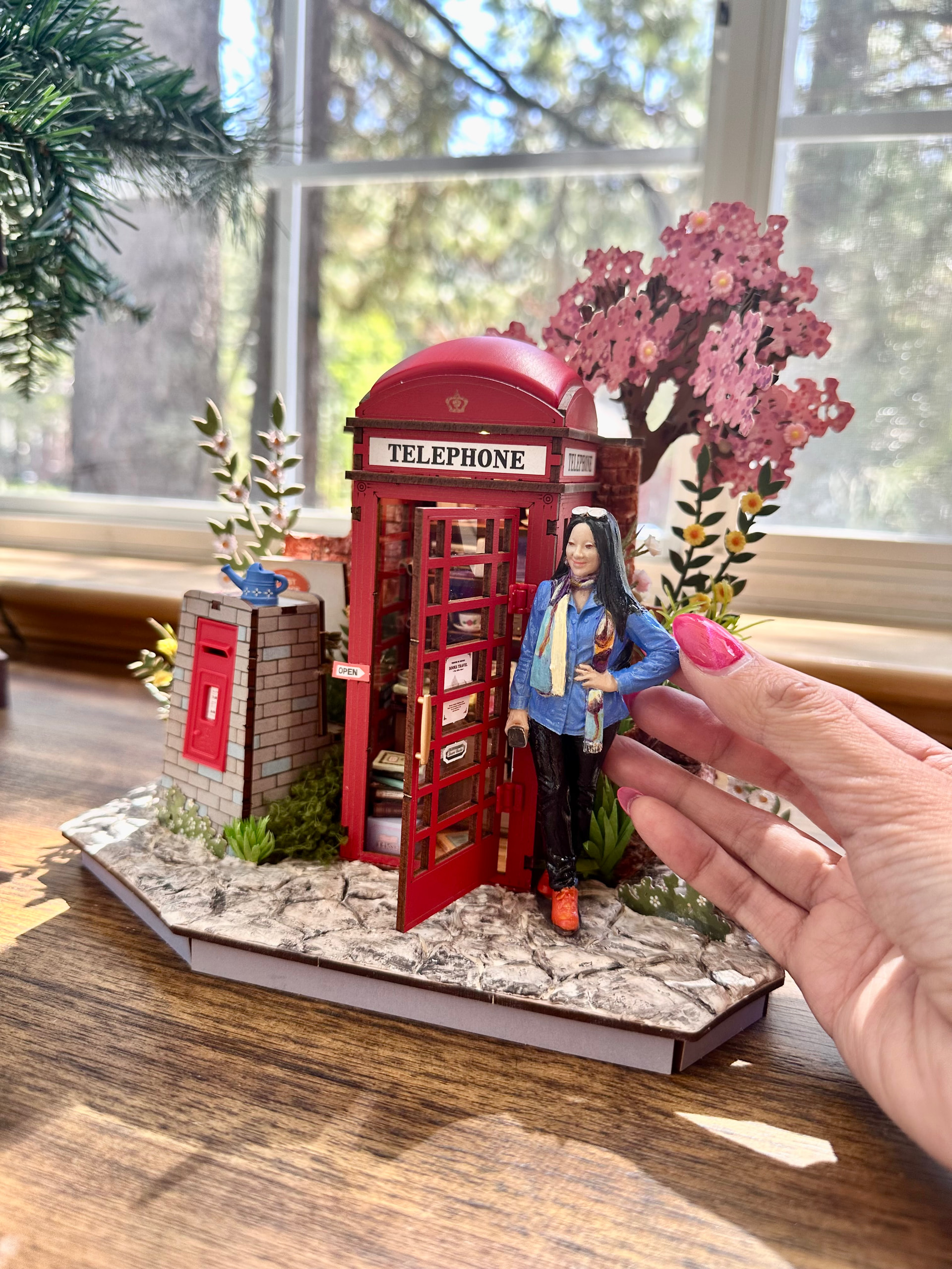 Hand-painted miniature figure being positioned beside the customized Blossom Book Booth