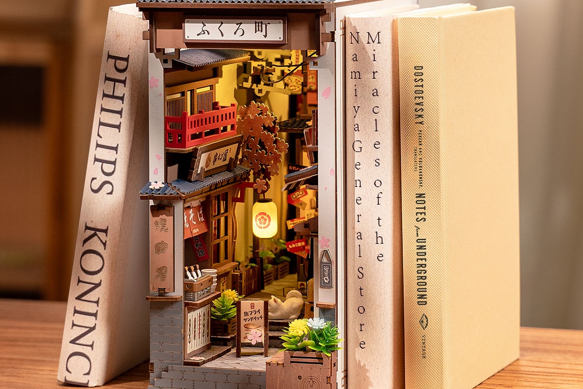 Rolife Sakura Wine Alley book nook framed by neutral books on a warm wooden shelf