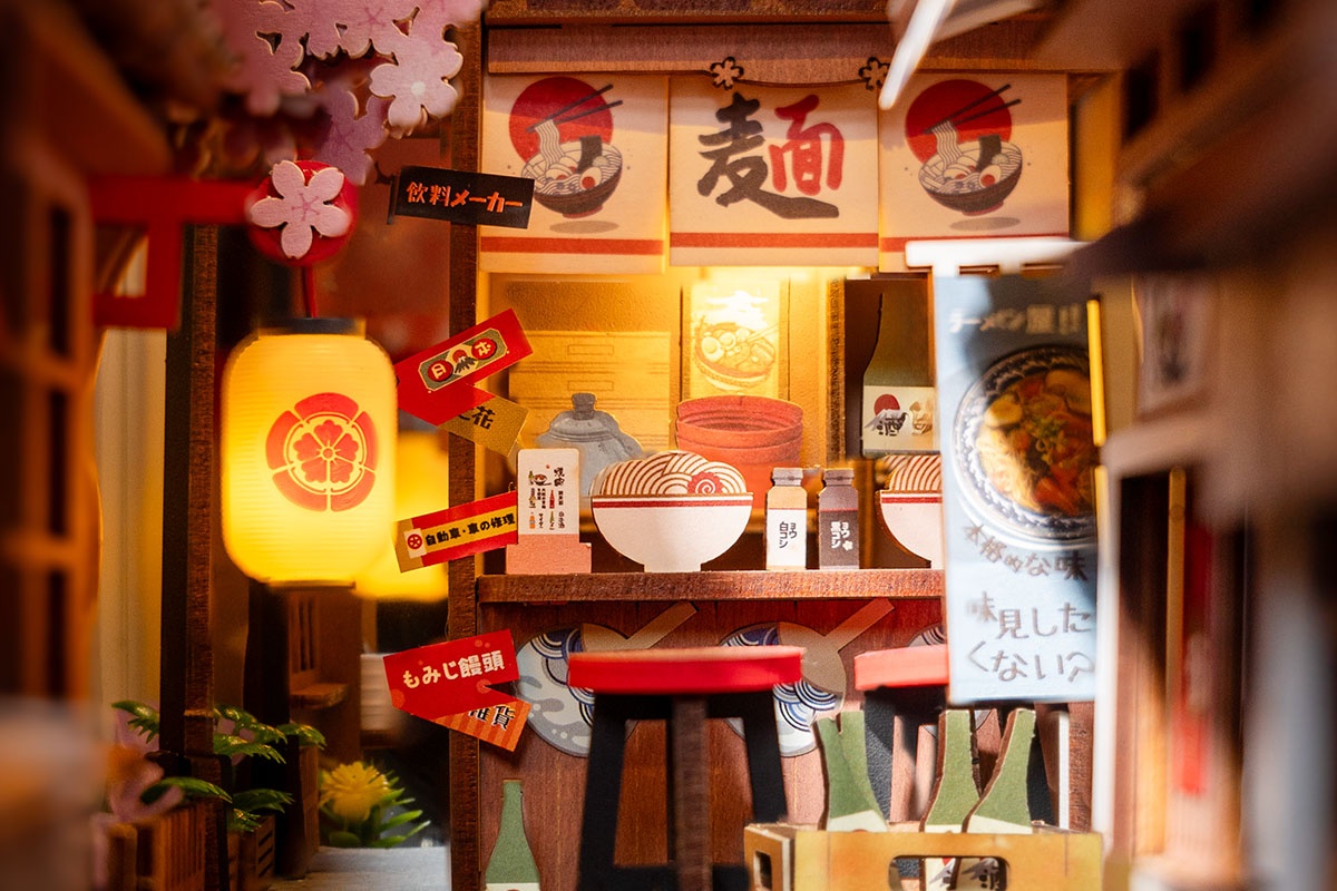 Close-up of warm lantern light and ramen counter details inside Sakura Wine Alley