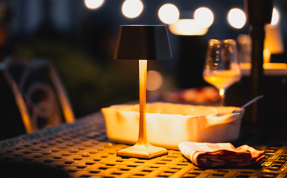 贝尔艾尔可充电台灯摆放在露台桌上，营造户外晚宴的氛围。