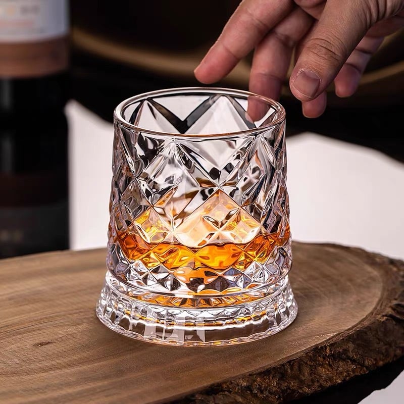 Diamond-cut whiskey glass filled with amber liquid on a wooden surface